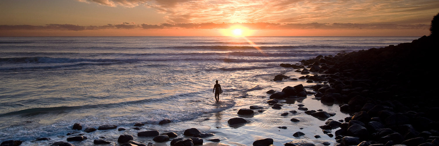 Sunrise over Burleigh Heads beach on the Gold Coast with a person walking along the shoreline