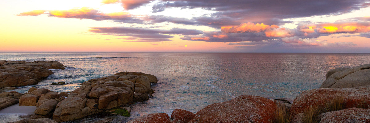 Rocky coastline at sunset in Tasmania, Australia with colorful clouds over the ocean