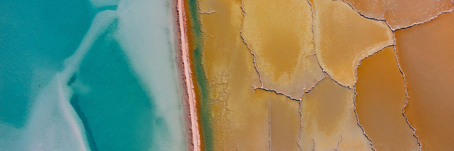 Aerial view of turquoise salt lake beside cracked golden salt flats
