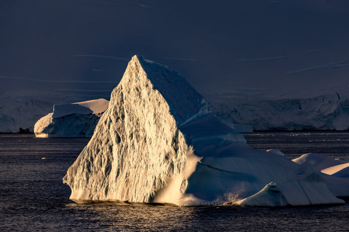 Antarctica, iceberg at sunset with dramatic light and frozen ocean foreground, fine art photography – Sean Scott Photography