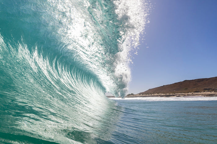 View from inside a breaking barrel wave at Quobba on Western Australia's Coral Coast, glassy teal water curling overhead with the headland visible through the break, photographed by Sean Scott