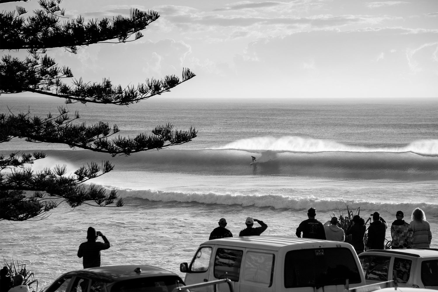 Australia, surfer riding clean ocean wave with spectators watching from shoreline in black and white, fine art photography – Sean Scott Photography